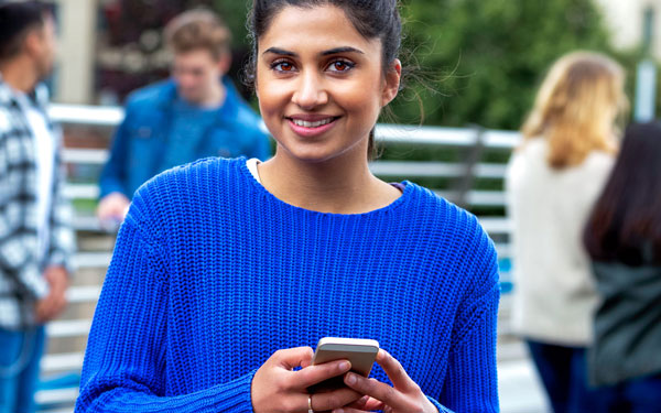 smiling student holding her phone in both hands