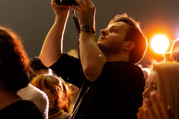 person taking picture in the middle of crowd